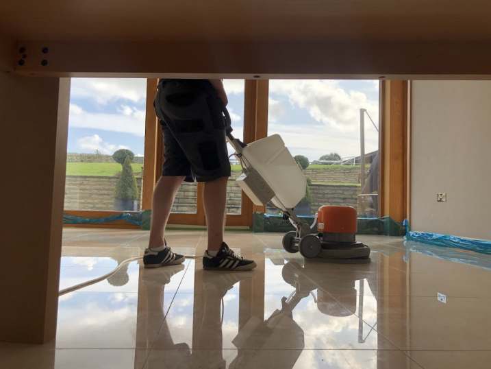 Highly polished marble floor by Hardfloor Restoration LTD with a professional floor buffer in action.