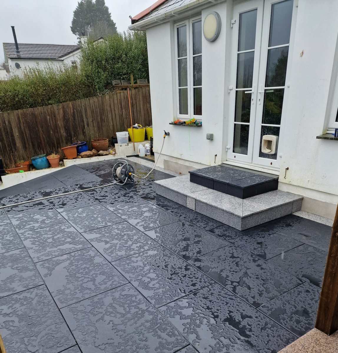 Newly sealed black limestone patio glistening with moisture, displaying the effectiveness of a high-quality sealer.